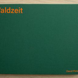 In grünem Leinen eingeschlagenes Buch, mit orangenem Schriftzug oben lins "Waldzeit" rechts unten der Name des Autos "David Peters"